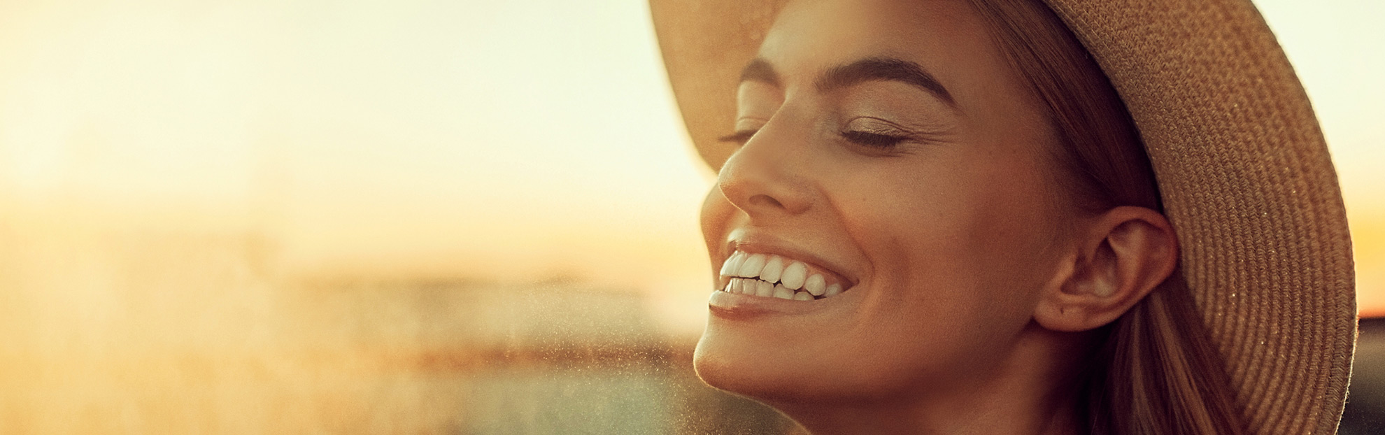 Smiling eye care patient wearing a hat at golden hour