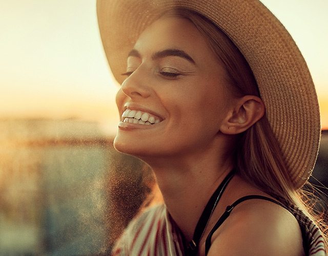 Happy woman with hat at golden hour: eye care patient
