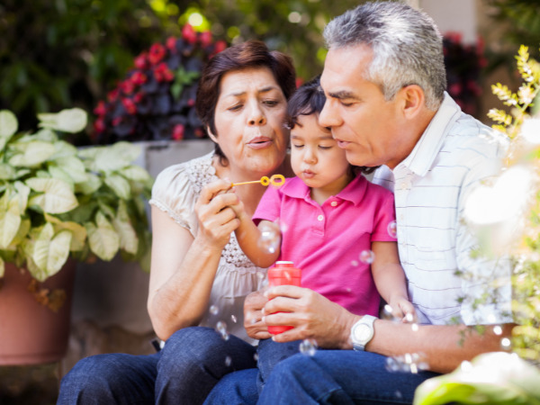 Mature Hispanic couple blow bubble with their granddaughter