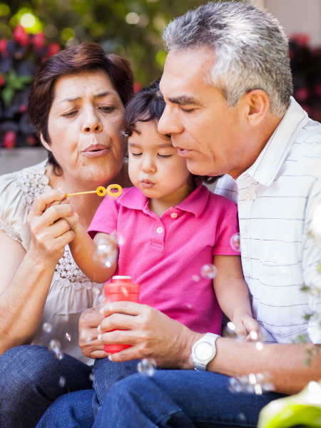 Mature Hispanic couple blow bubble with their granddaughter