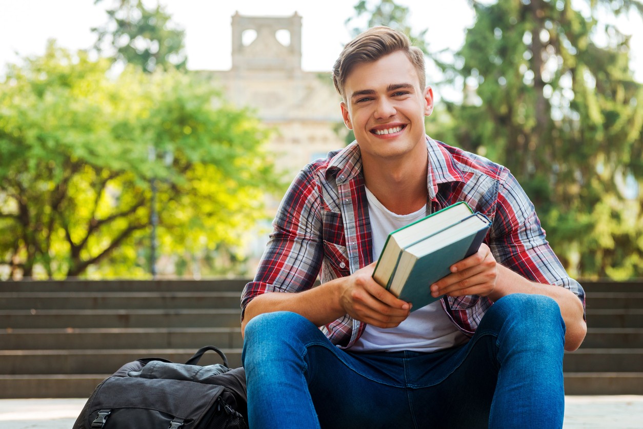 male-college-student-holding-books